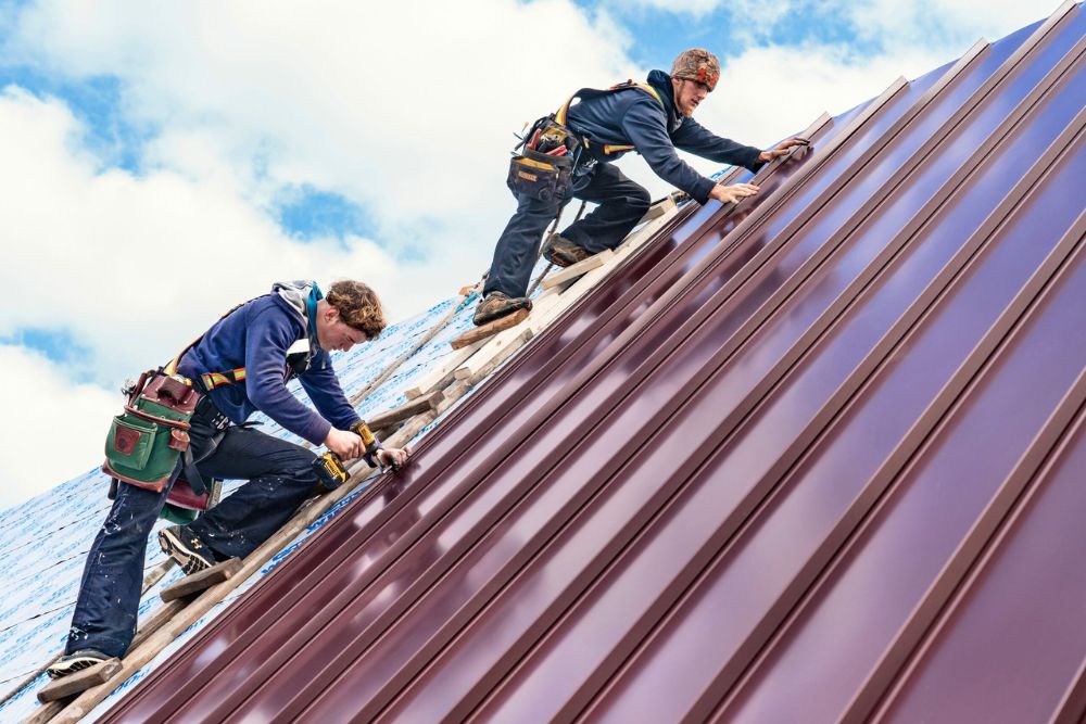 Two professionals working on a metal roof, highlighting our emergency roofing services available in Akron, OH.