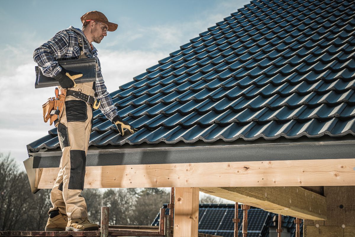 A skilled man on a rooftop holds a tool, symbolizing expertise and assurance in home maintenance and repair tasks.